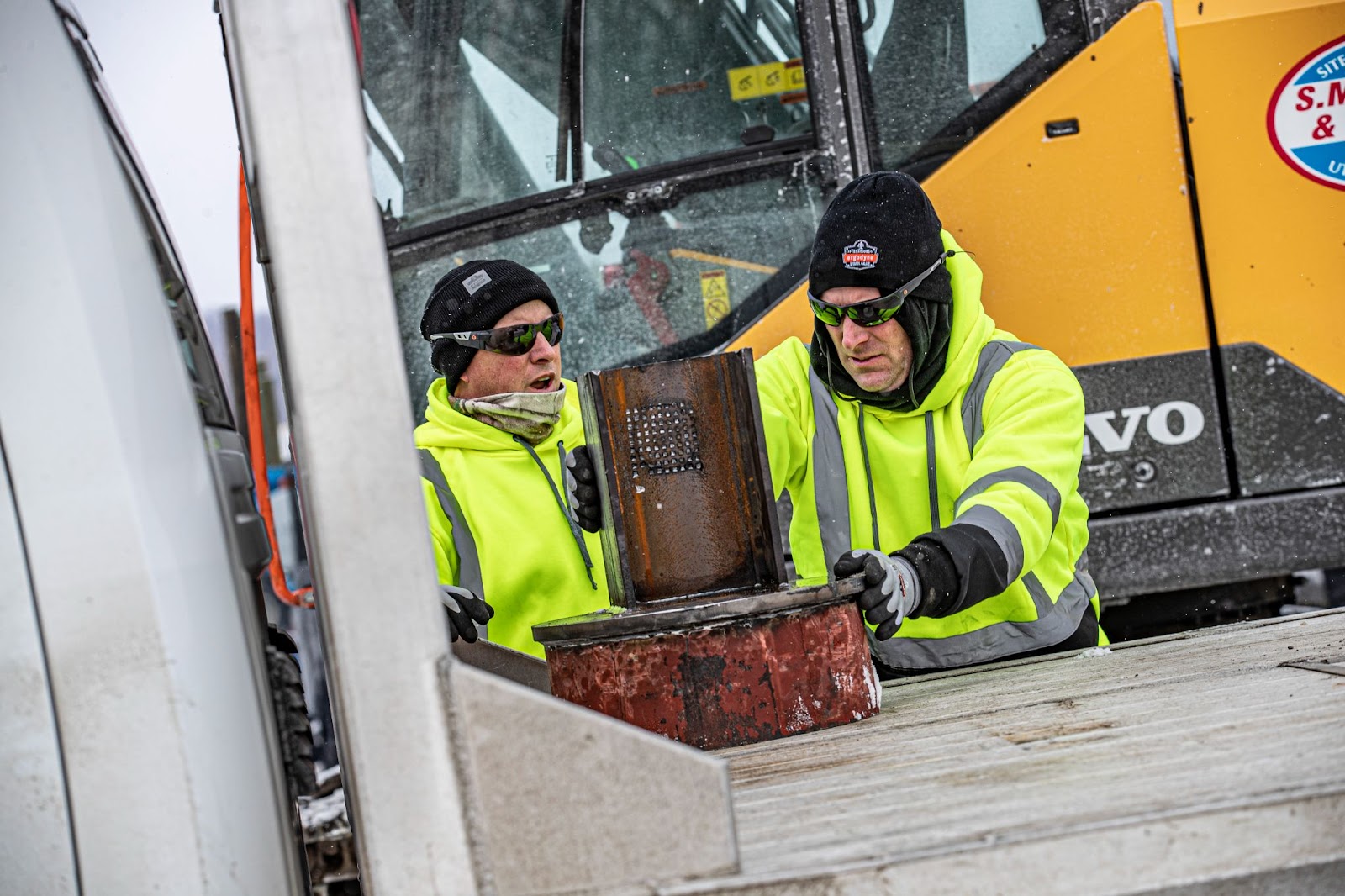 Two workers wearing hi vis sweatshirts and safety glasses while fixing machinery