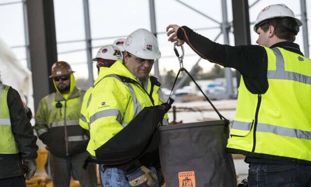 Workers inspecting a hoist bucket on a job site